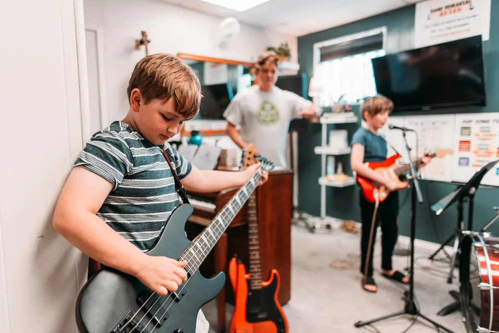 Guitar students practicing together in a band rehearsal space